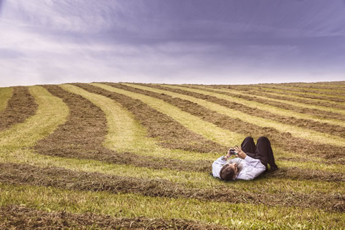 Picture of a man with a digital device lying in a field